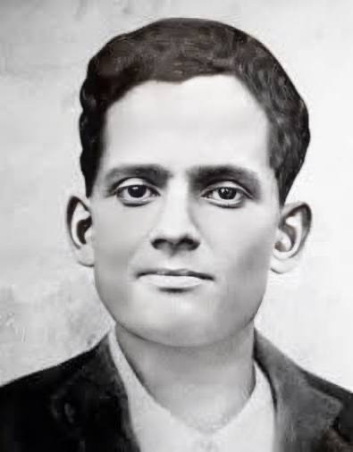 A retouched close portrait of Jatindra Nath Das, facing forward, wearing a dark jacket over a light collarless shirt.